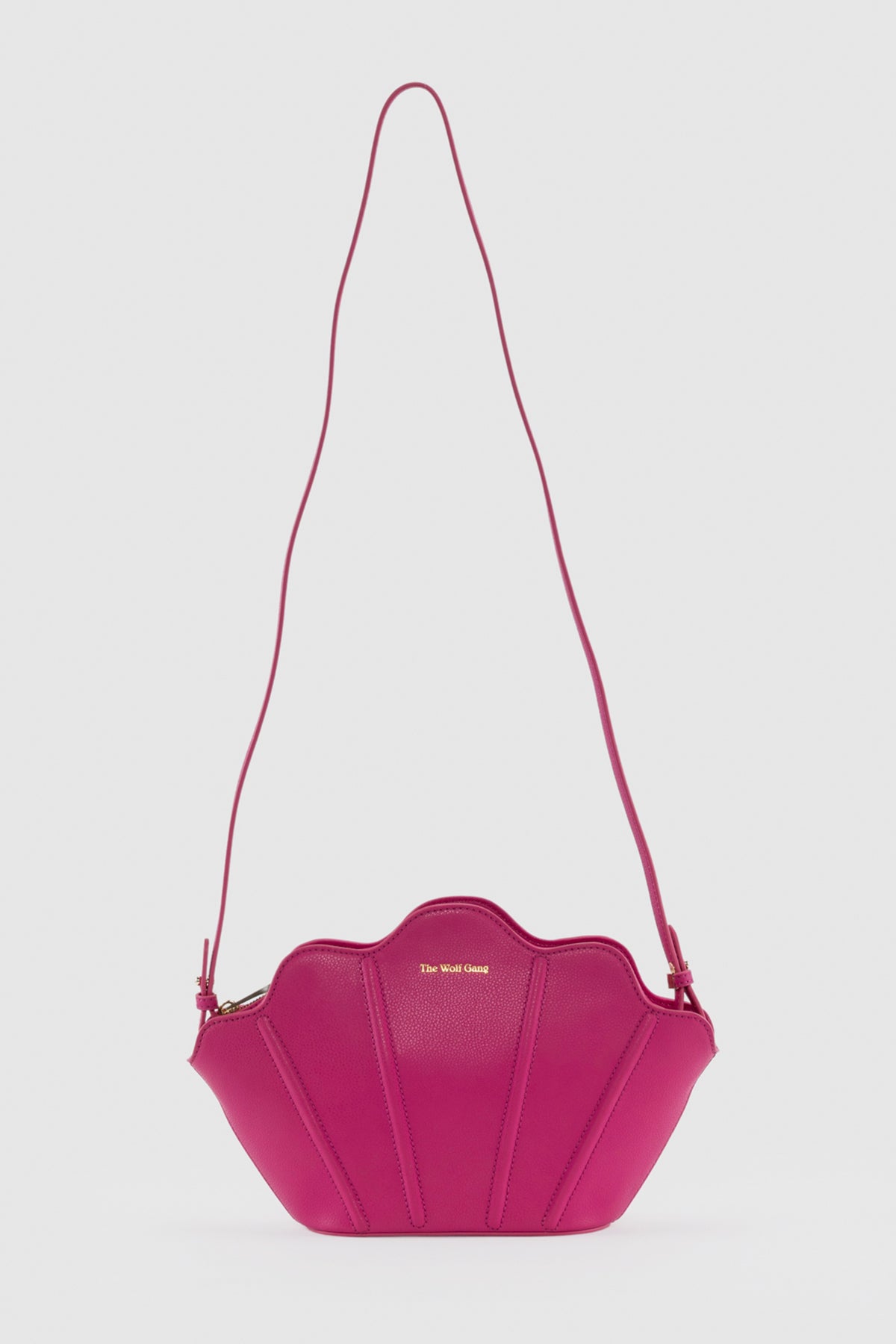 Luxury pebbled leather Suri Bag shell-shaped clutch in Flamingo Pink, with scalloped edge, gold zip, detachable crossbody strap, and ridged detail.