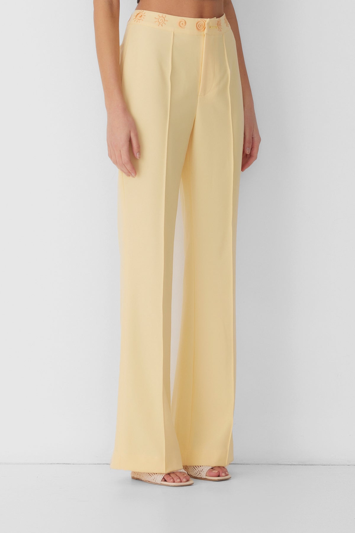 Women’s highwaisted Butter Yellow Irida Bootcut Pants with pin tuck detail and embroidered waistband—wear solo or as a matching set with Irida Vest Dress.