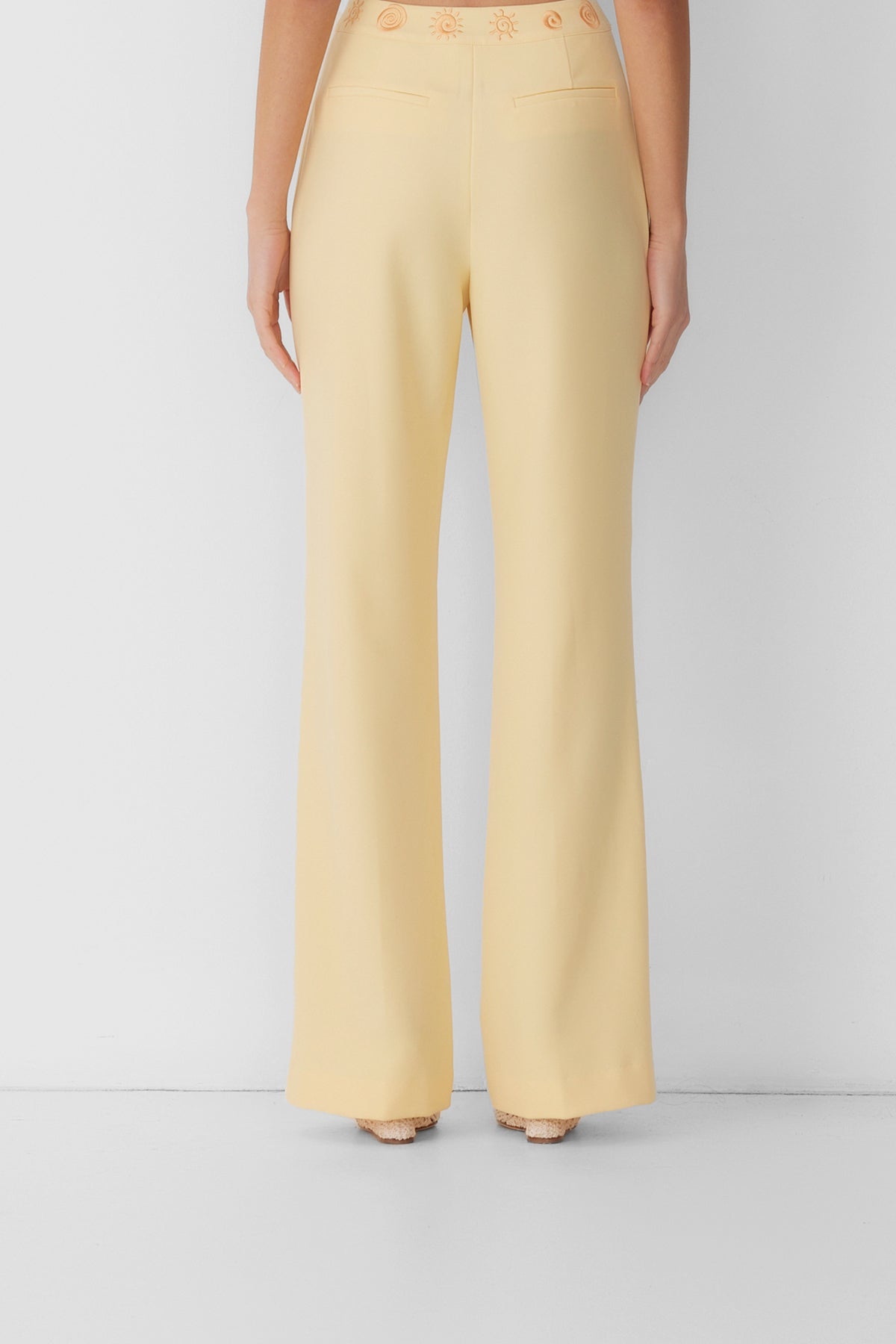 Women’s highwaisted Butter Yellow Irida Bootcut Pants with pin tuck detail and embroidered waistband—wear solo or as a matching set with Irida Vest Dress.