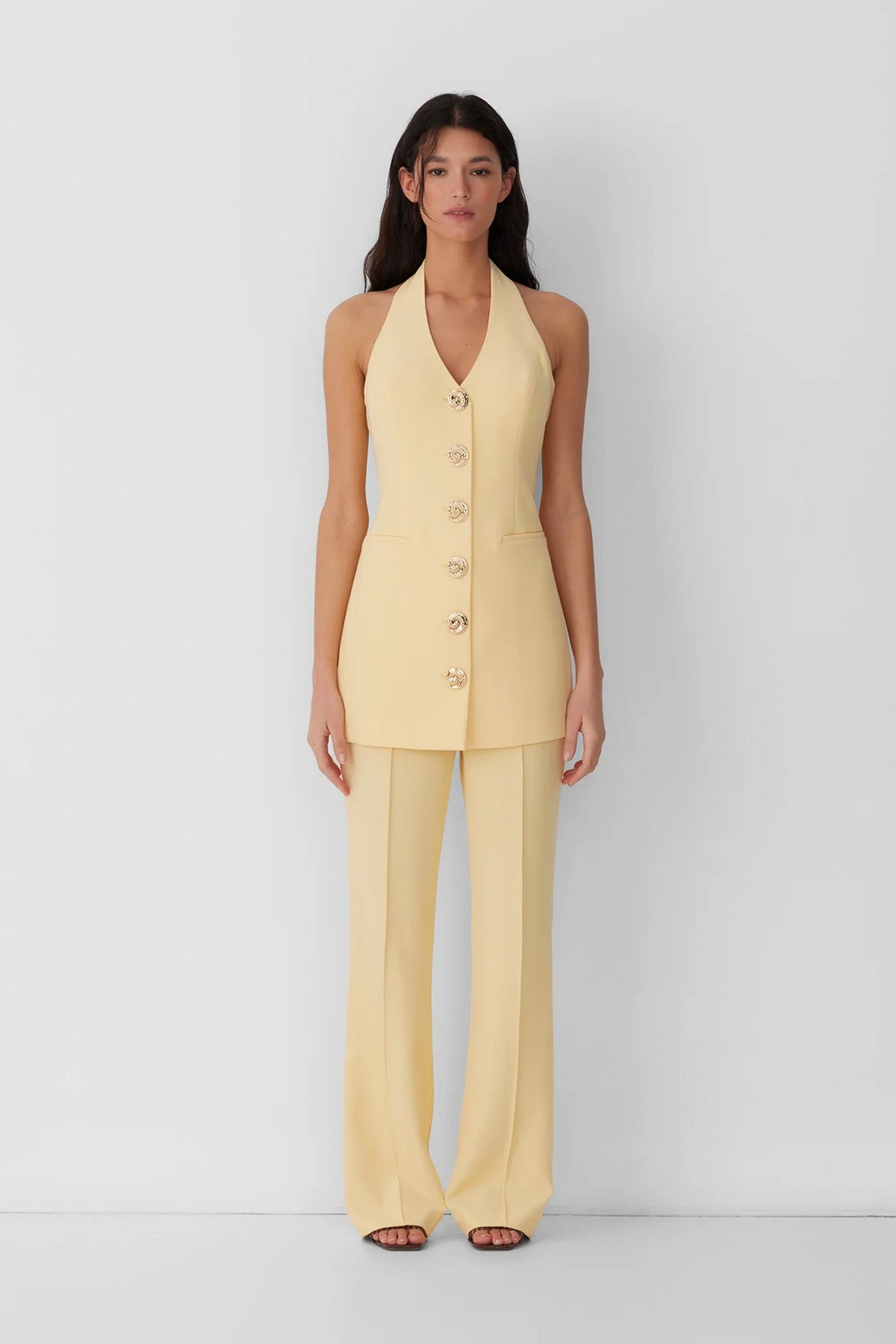 Best-selling women’s Butter Yellow Irida mini halter neck vest dress with gold swirl buttons, tie-back, and front welt pocket—wear alone or with matching pants.