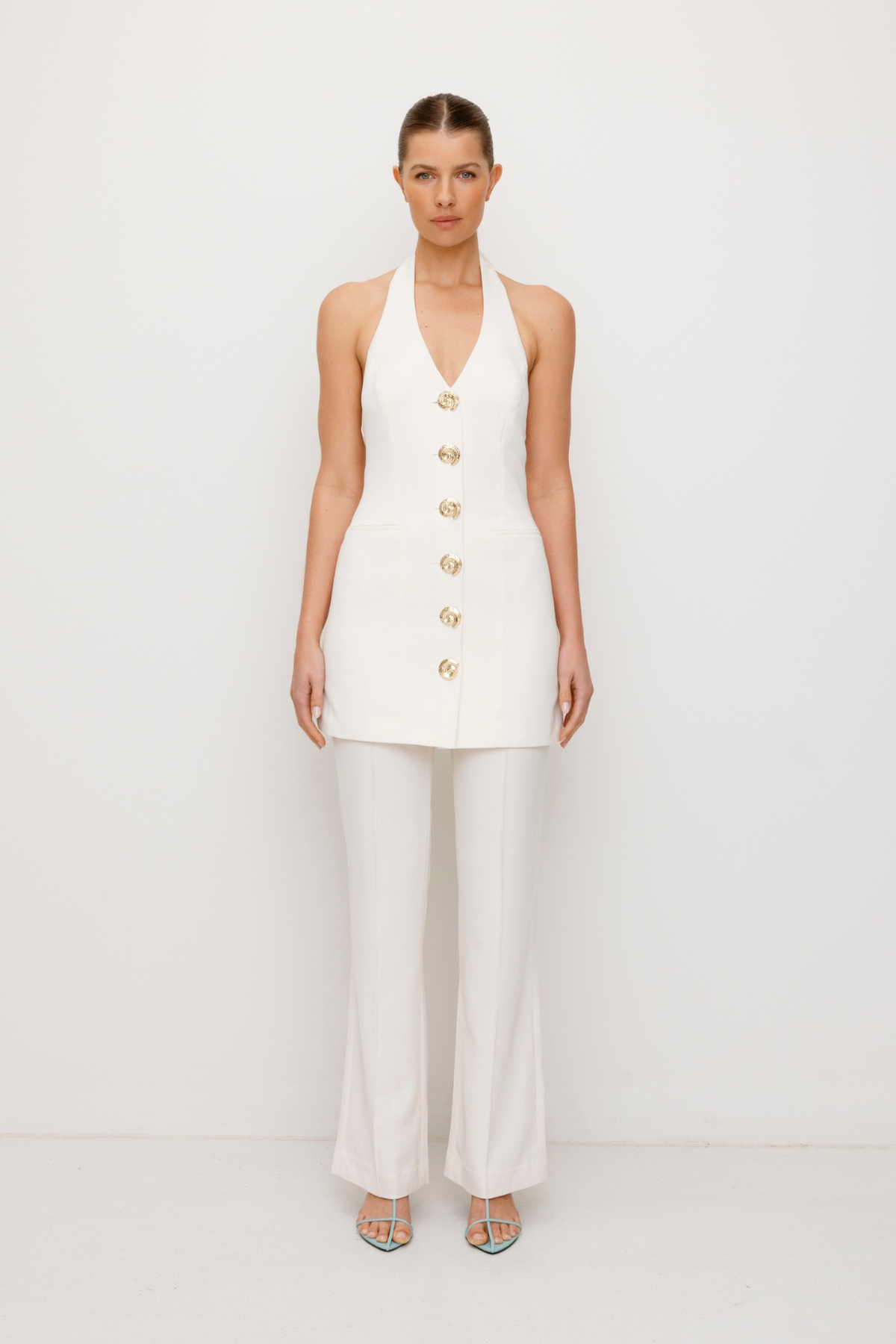 Best-selling women’s Ivory White Irida mini halter neck vest dress with gold swirl buttons, tie-back, and front welt pocket—wear alone or with matching pants. Perfect for Brides.