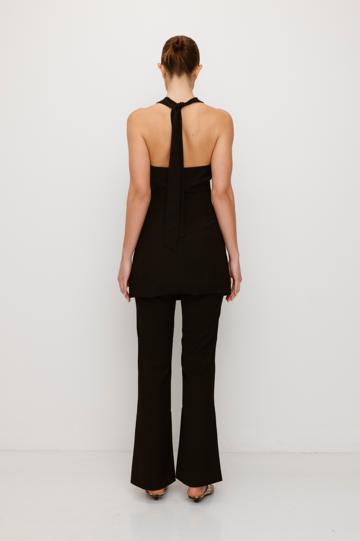 Women’s highwaisted Black Noir Irida Bootcut Pants with pin tuck detail and embroidered waistband—wear solo or as a matching set with Irida Vest Dress.