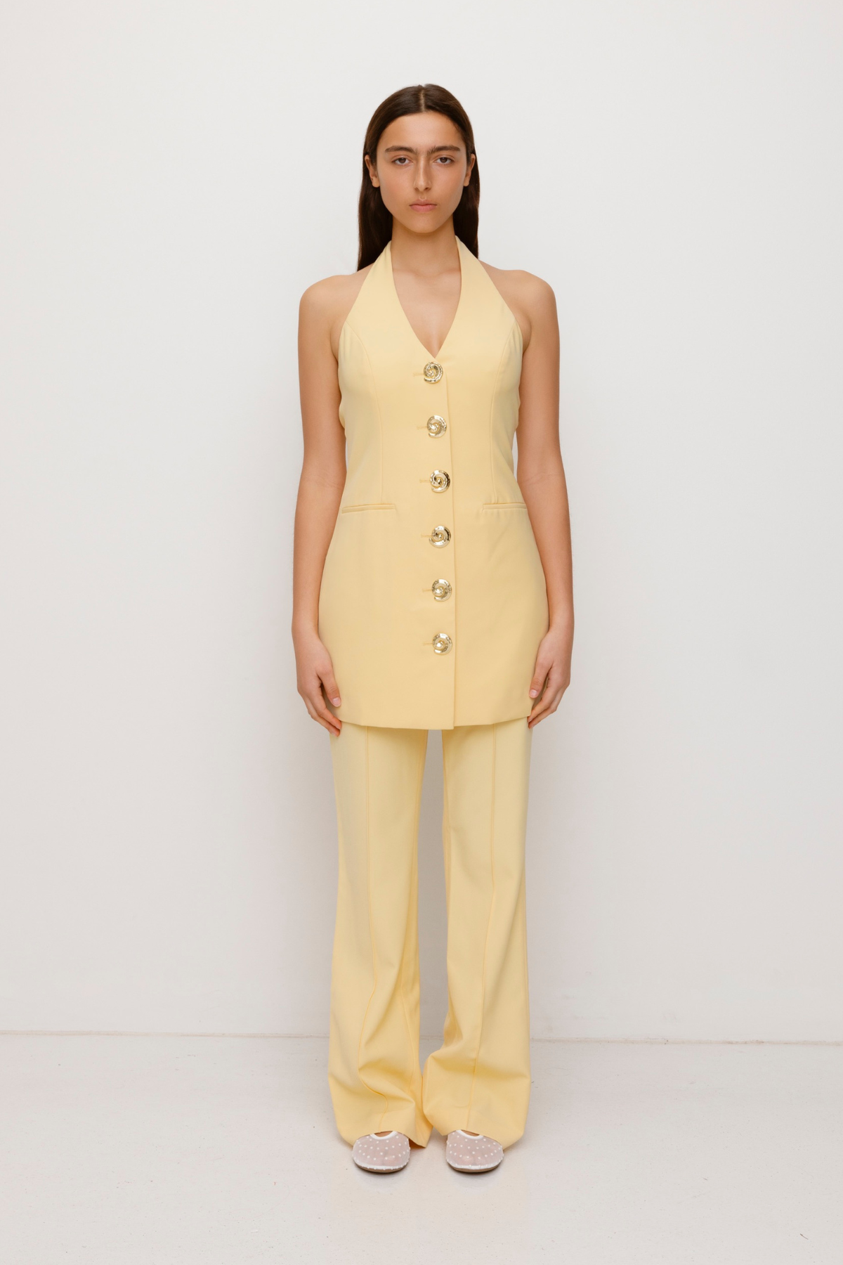 Women’s highwaisted Butter Yellow Irida Bootcut Pants with pin tuck detail and embroidered waistband—wear solo or as a matching set with Irida Vest Dress.