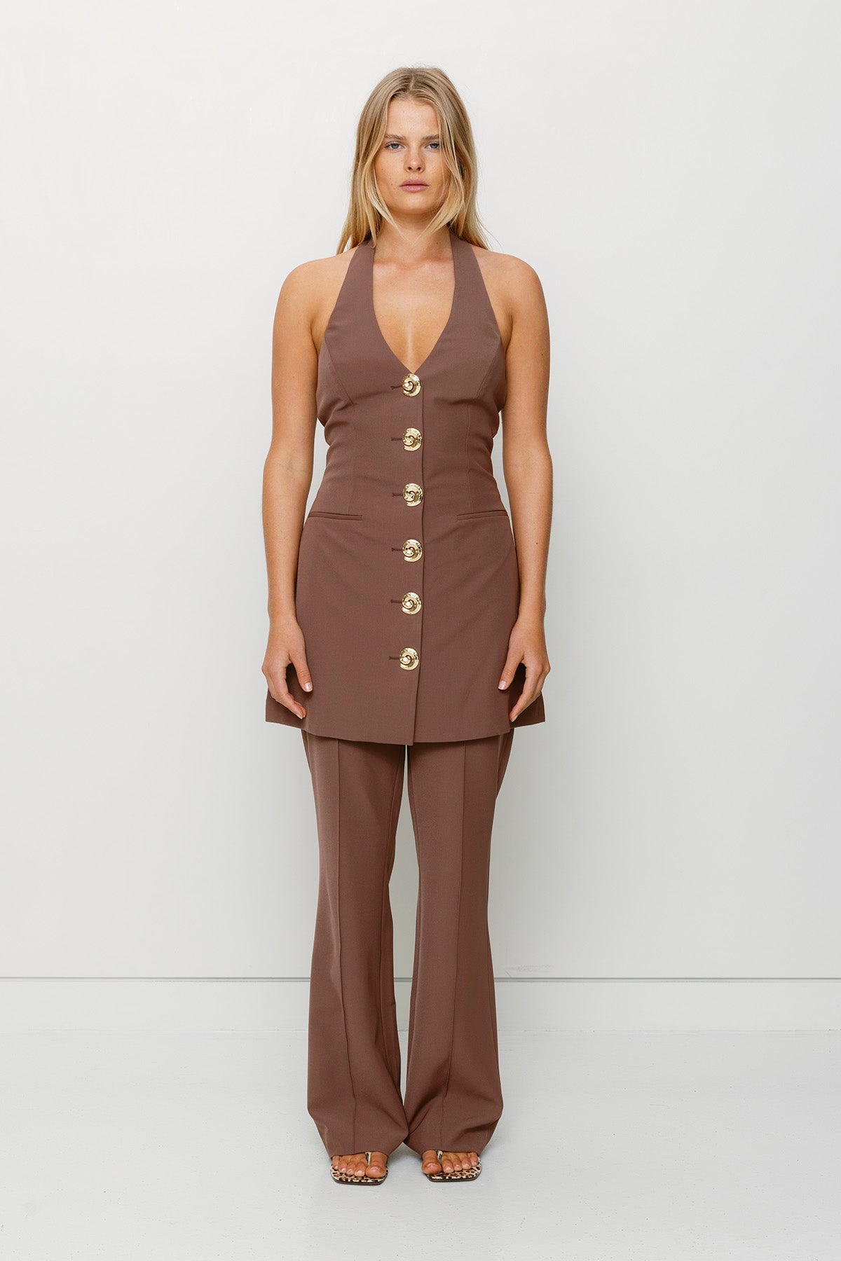Best-selling women’s Chocolate Brown Irida mini halter neck vest dress with gold swirl buttons, tie-back, and front welt pocket—wear alone or with matching pants.