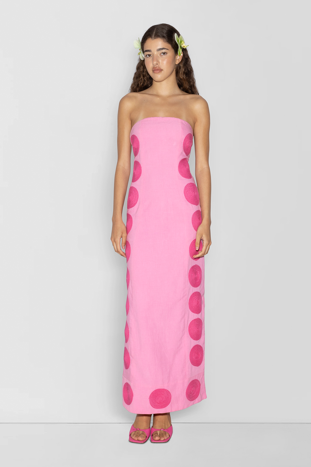 Woman wearing Pink linen cotton maxi dress with contrast embroidery and shaped bust.