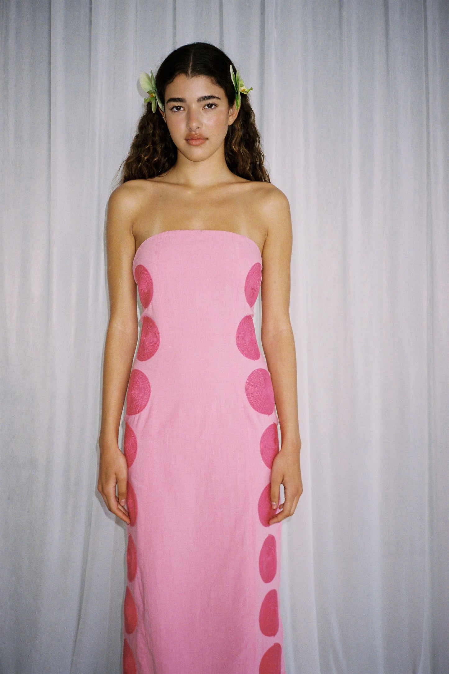 Woman wearing Pink linen cotton maxi dress with contrast embroidery and shaped bust.