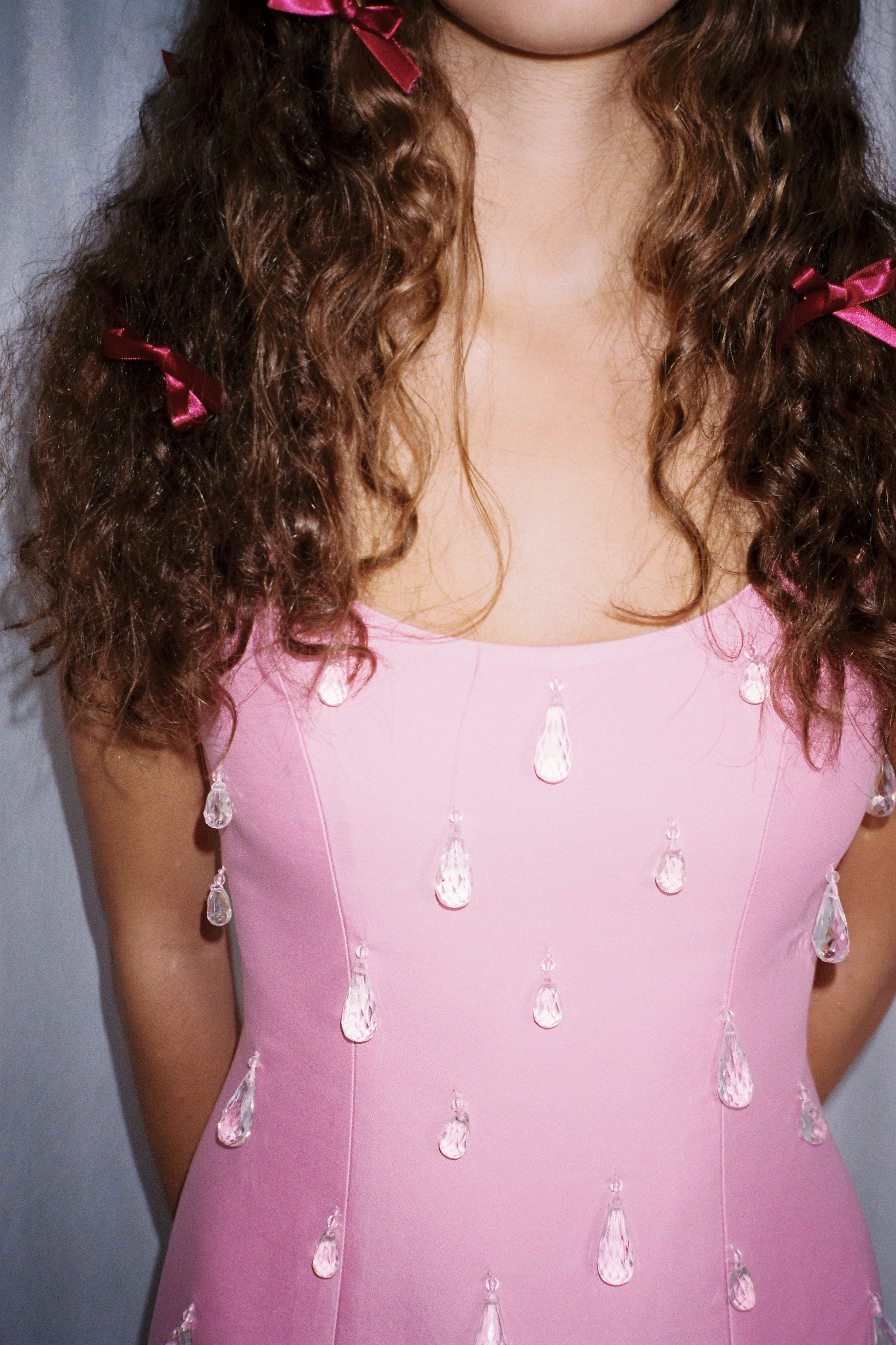 Woman wearing Pink beaded mini dress with satin finish and teardrop embellishments.
