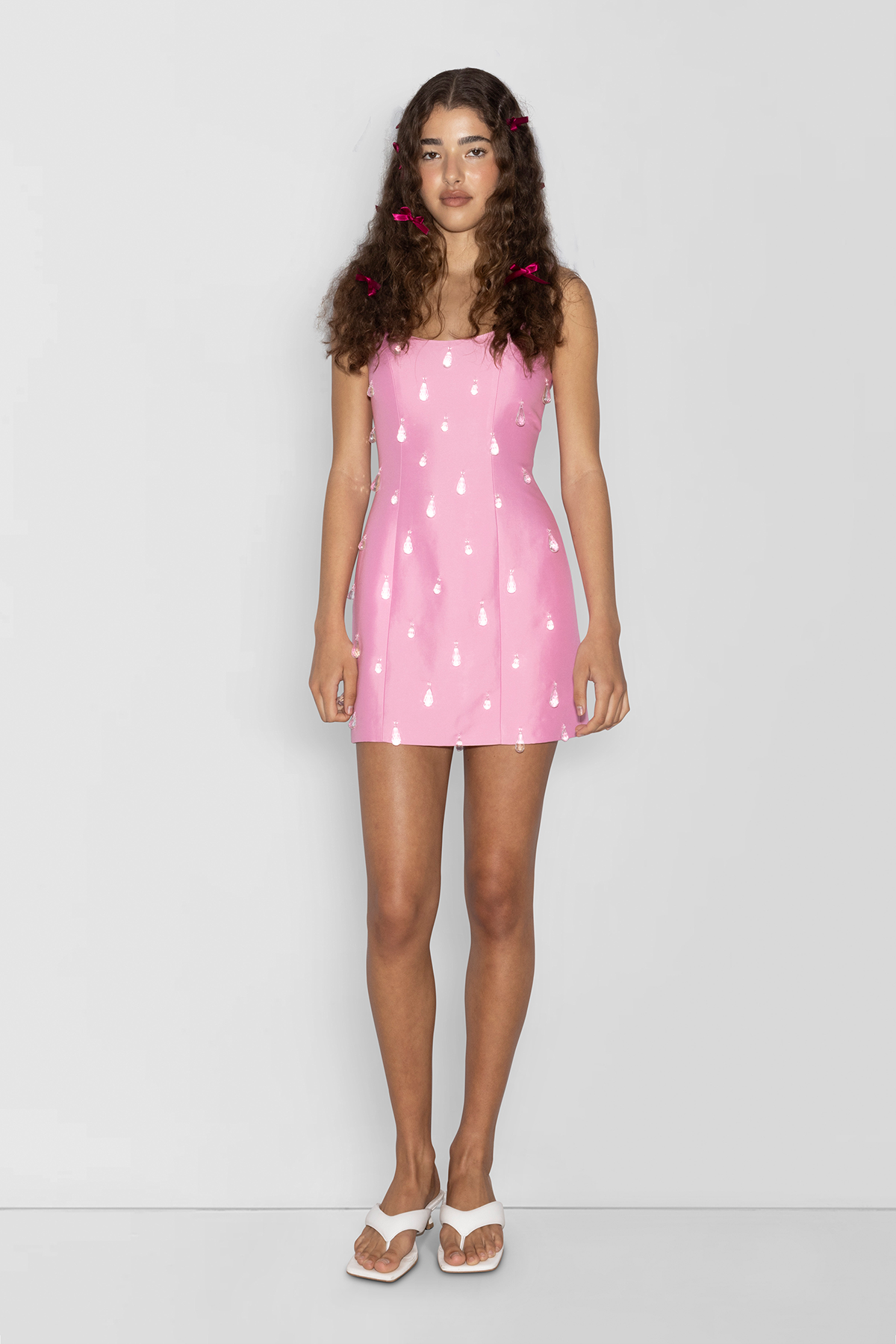 Woman wearing Pink beaded mini dress with satin finish and teardrop embellishments.