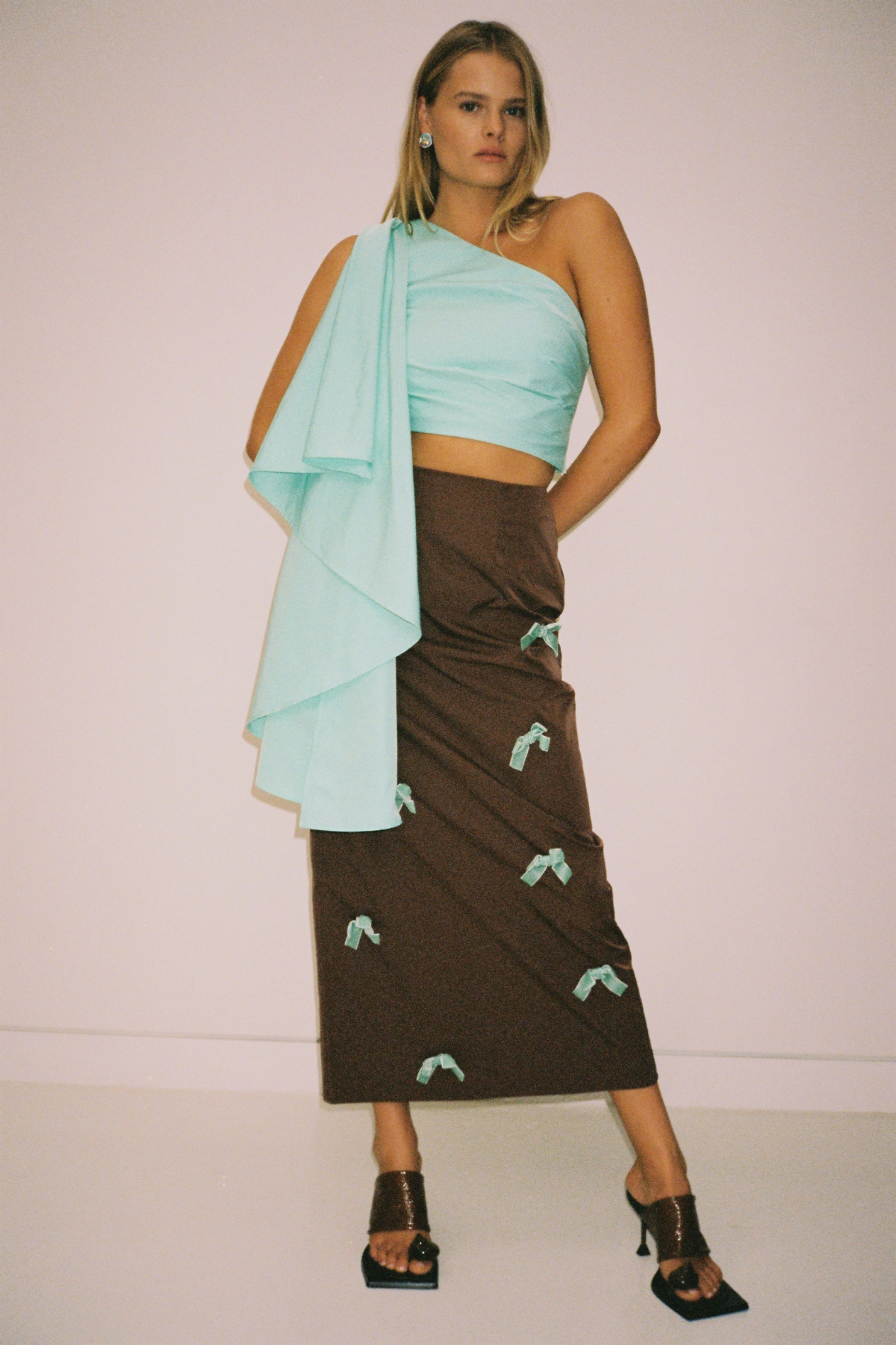 Brown high-waisted midi skirt with blue velvet bows by The Wolf Gang, styled to match the Amar One Shoulder Top.