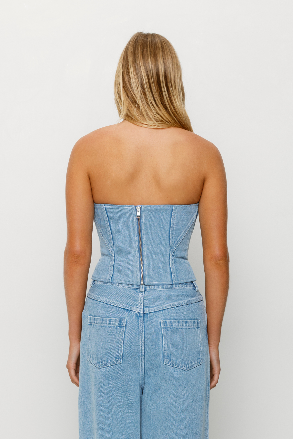 Corset-style denim bustier with boning, functional zip, and custom TWG embroidery by The Wolf Gang, pairs with matching denim jeans.