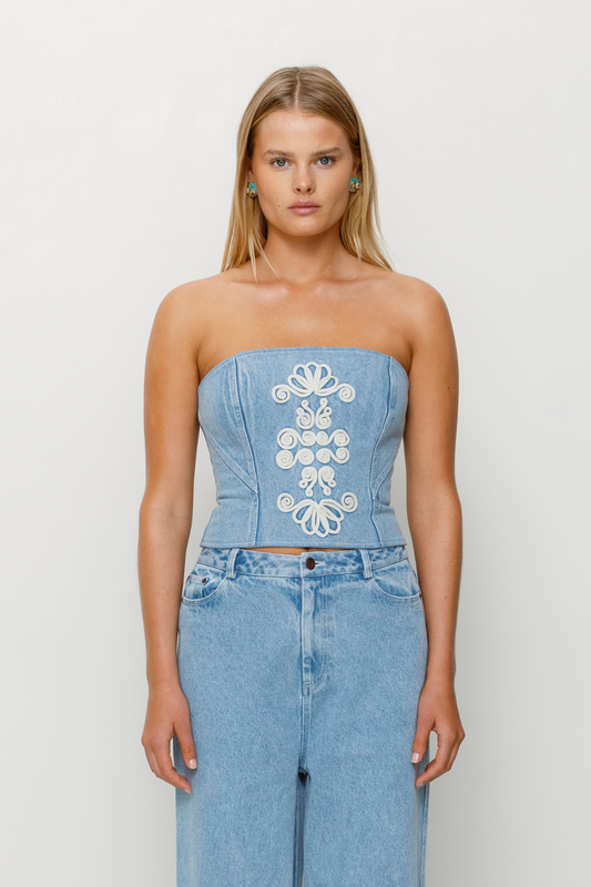 Corset-style denim bustier with boning, functional zip, and custom TWG embroidery by The Wolf Gang, pairs with matching denim jeans.