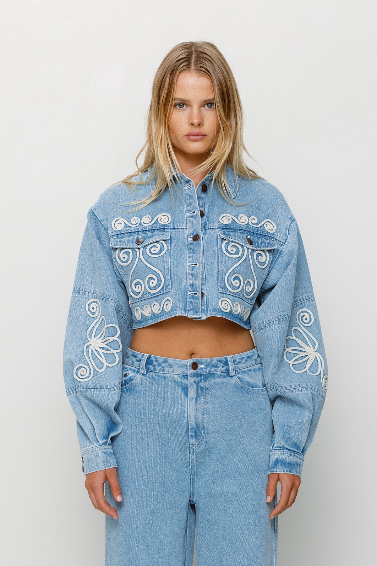 Cropped cotton denim jacket with oversized balloon sleeves and custom embroidery by The Wolf Gang, pairs with matching barrel jeans.