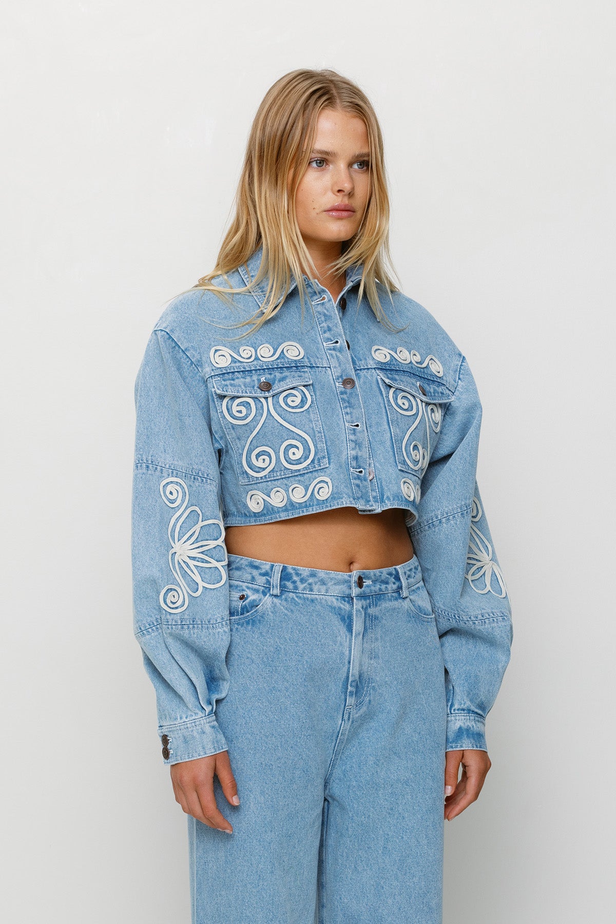 Cropped cotton denim jacket with oversized balloon sleeves and custom embroidery by The Wolf Gang, pairs with matching barrel jeans.