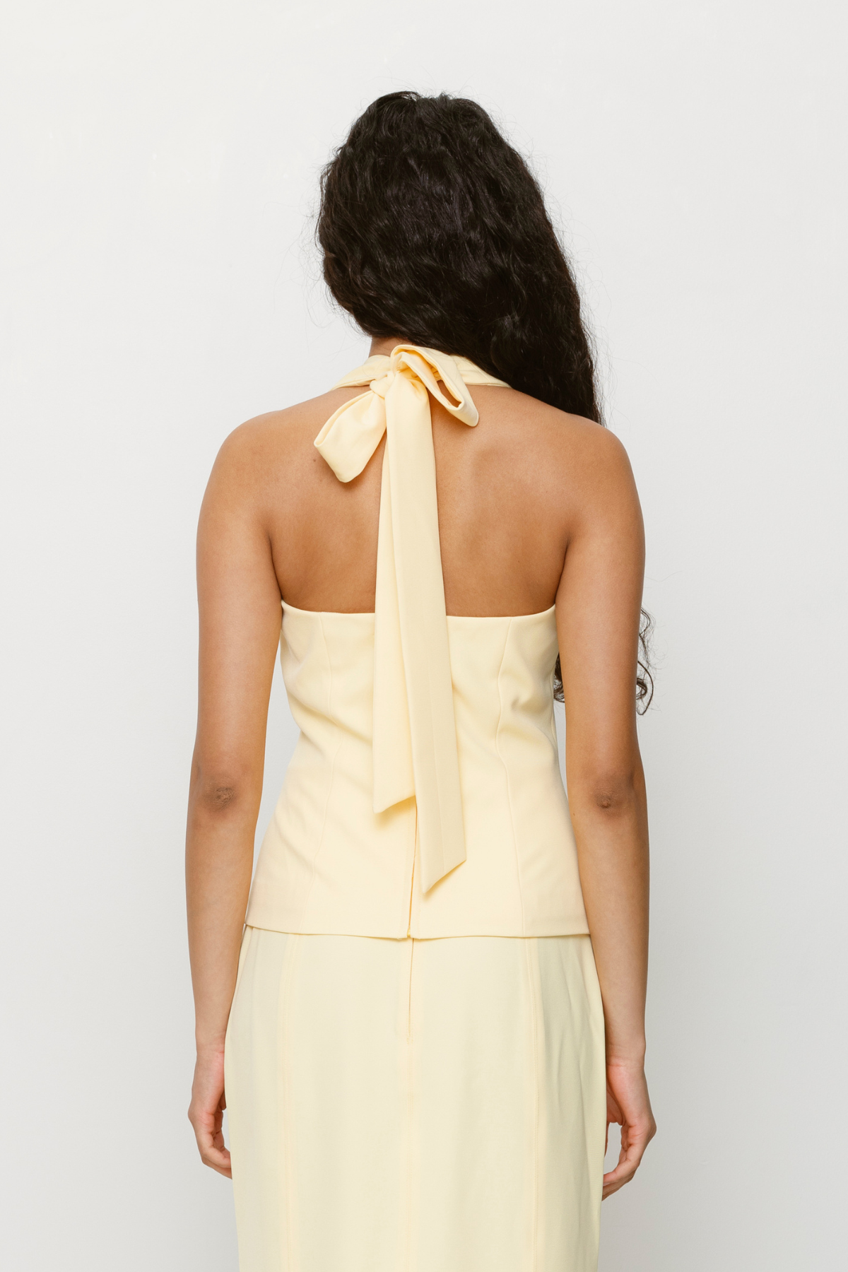 Halterneck vest top in butter yellow or charcoal grey with asymmetric closure and custom hardware by The Wolf Gang, styled with jeans or matching skirt.