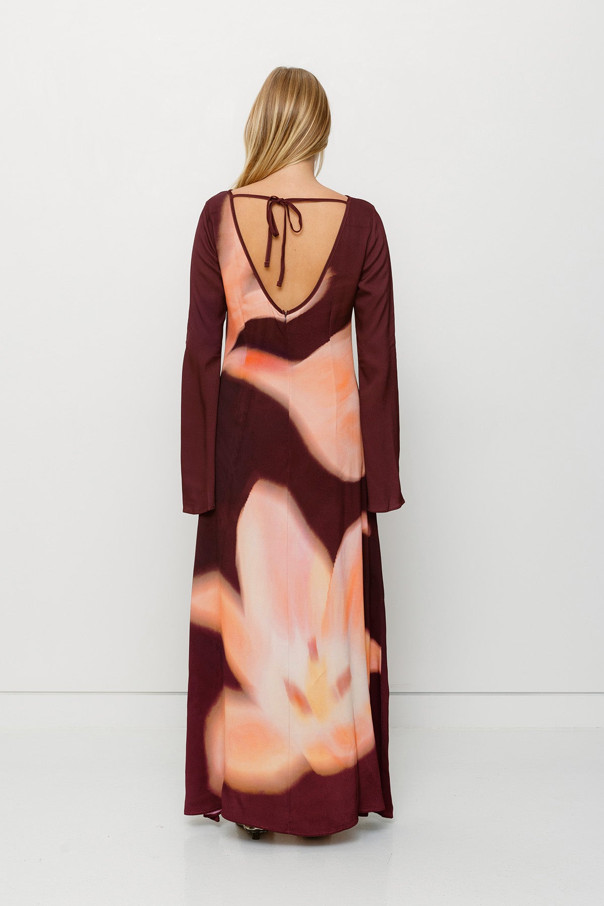 Silky sleeved maxi dress with custom floral TWG print and adjustable back tie, designed for a sleek, glamorous fit.