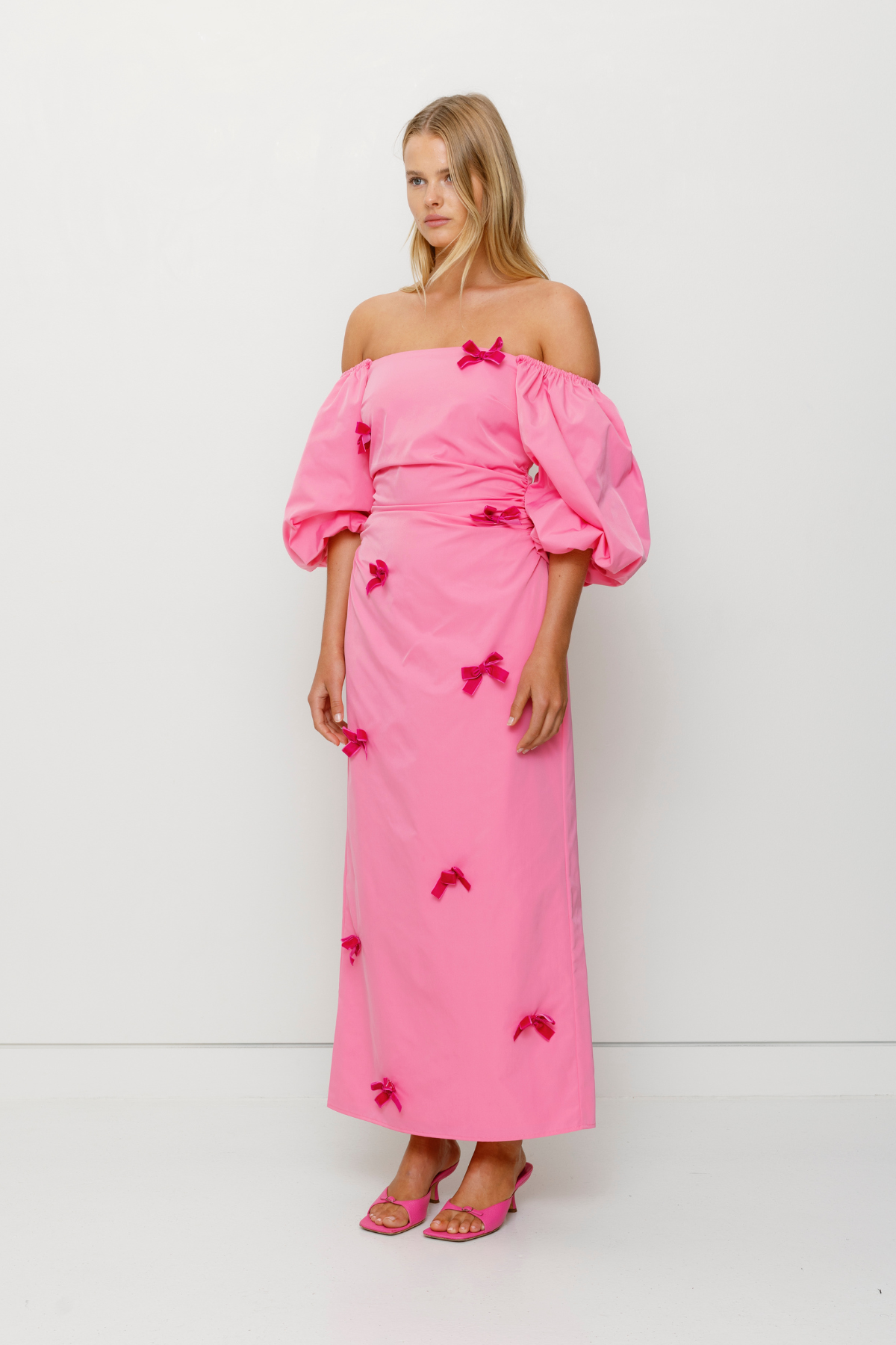 Mid-length off-shoulder dress with elasticated puff sleeves and velvet bow detail by The Wolf Gang, in pink, red, and black.