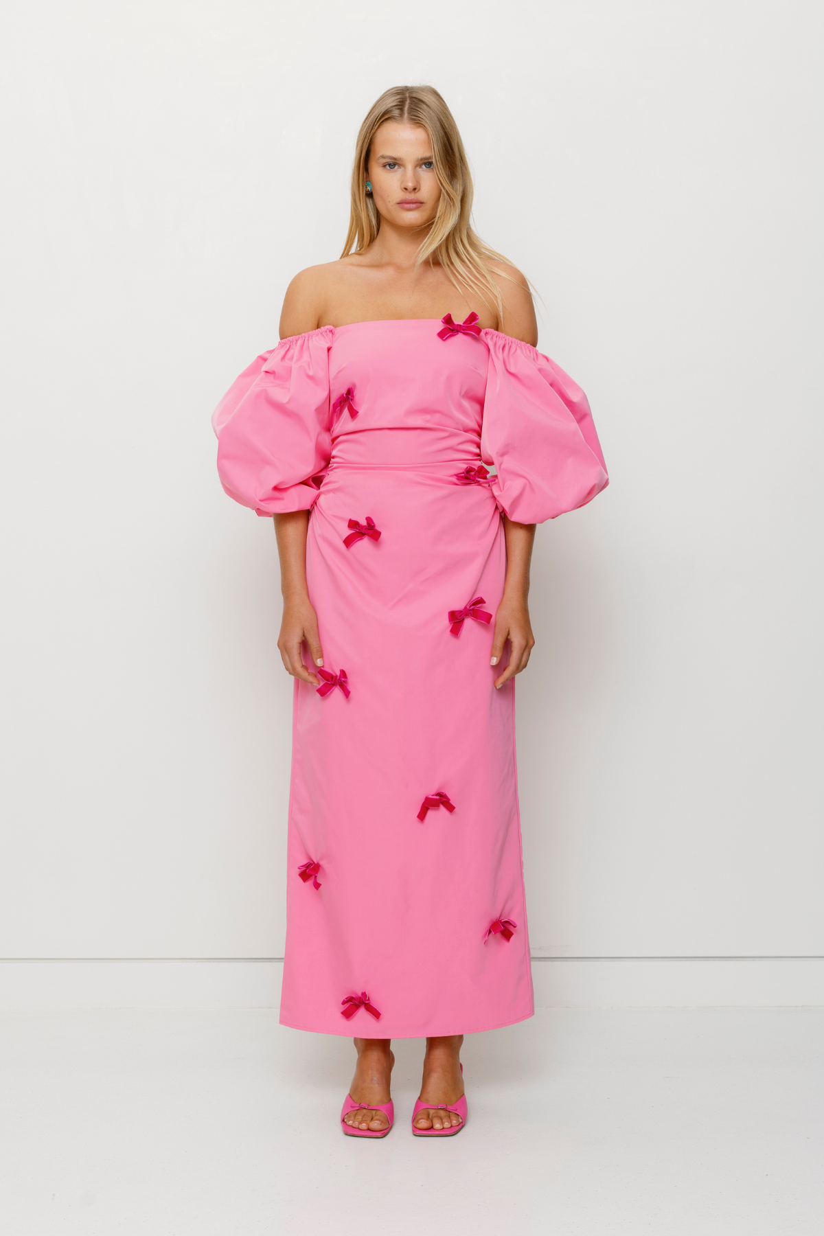 Mid-length off-shoulder dress with elasticated puff sleeves and velvet bow detail by The Wolf Gang, in pink, red, and black.
