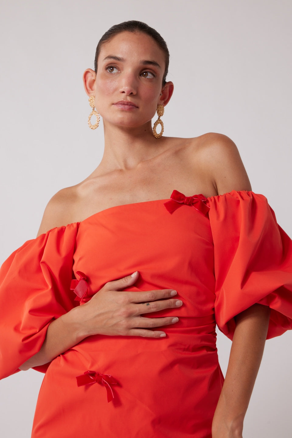 Mid-length off-shoulder dress with elasticated puff sleeves and velvet bow detail by The Wolf Gang, in pink, red, and black.