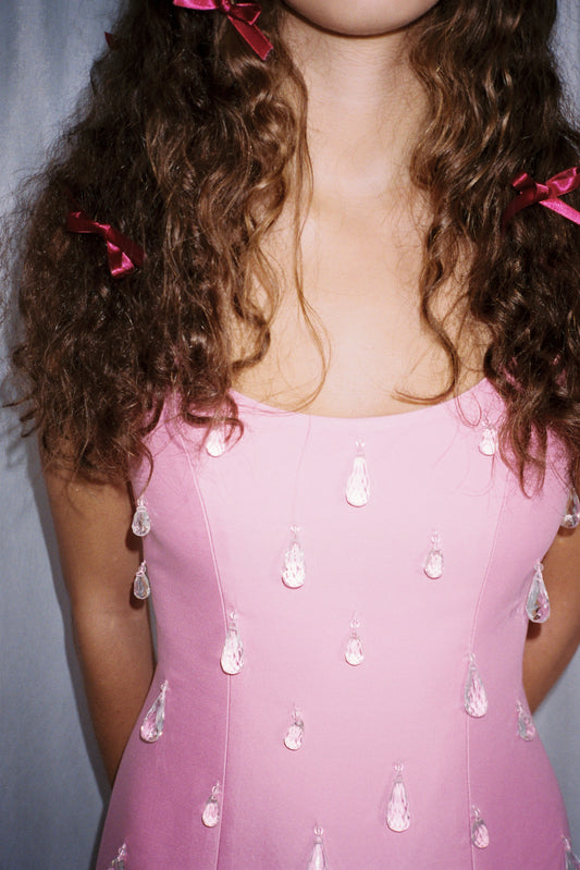 Woman wearing Pink beaded mini dress with satin finish and teardrop embellishments.