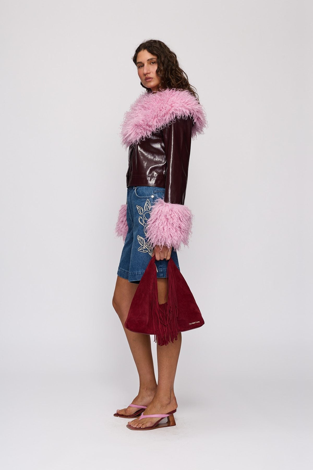 Novia Fringe Handbag in Berry by The Wolf Gang – styled side view, carried by hand (with Abrigo Jacket)