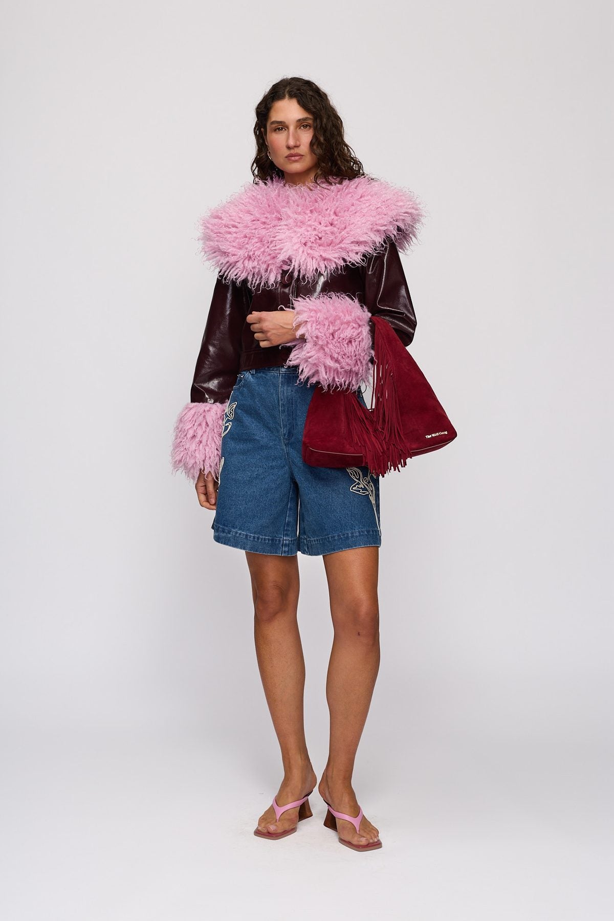 Novia Fringe Handbag in Berry by The Wolf Gang – styled front view, held at the hip